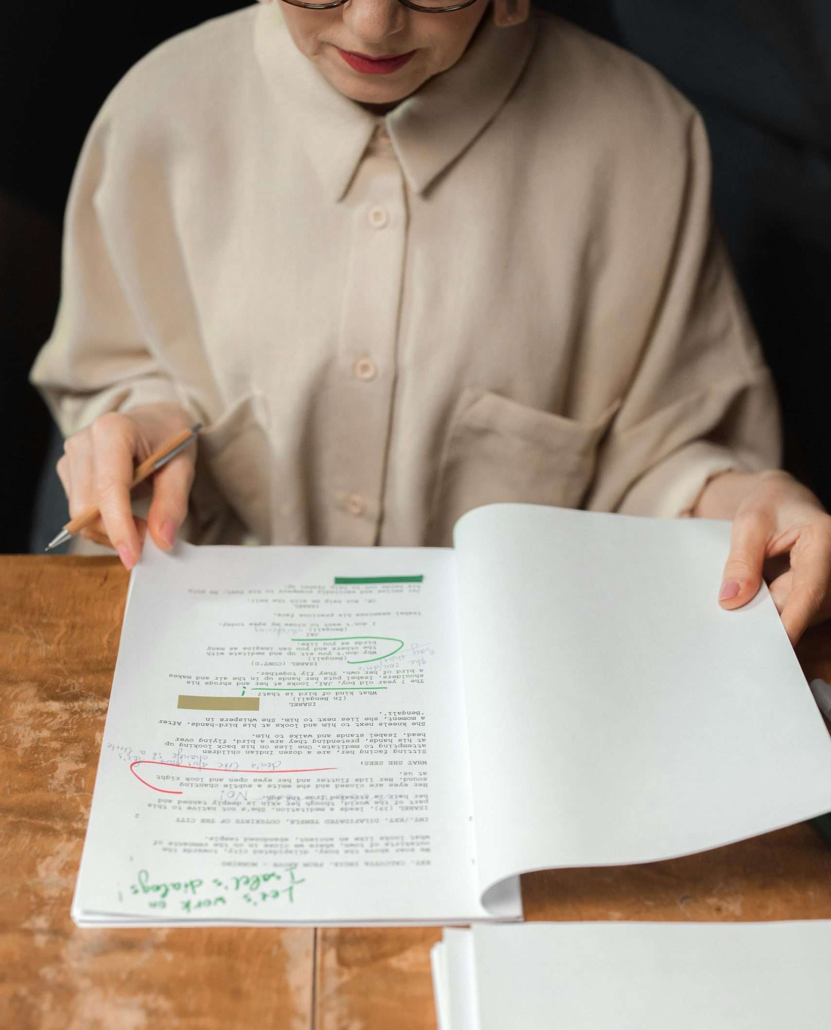 Senior woman reviewing a screenplay script with notes and edits, showcasing expertise.